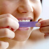 Blanqueamiento dental con tiras blanqueadoras moradas de Diamond Smile en los dientes de una mujer